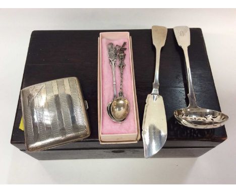 Silver cigarette case, silver fish knife, silver pierced bowl ladle and two white metal souvenir spoons, within wooden work b