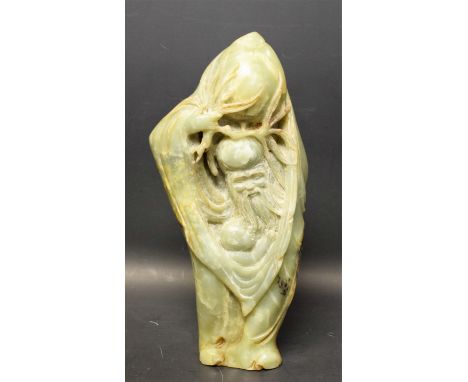 A 19th century Chinese russet jade carving, of Shou Lao, holding a giant peach, a child under his robe, 28cm high