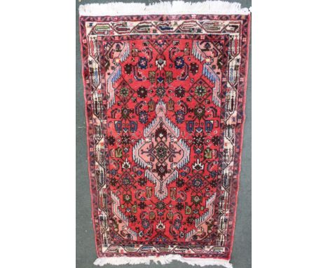 A Persian design red ground rug, fringed &amp; bordered, 135cm x 80cm