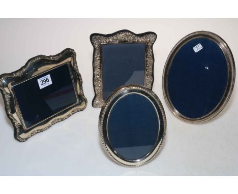 Four silver easel photograph frames, two oval and two ornate shaped.