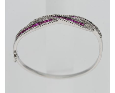 An 18ct white gold ruby and diamond set cross-over bangle.