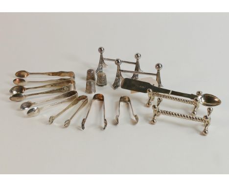 A collection of solid silver items including two pairs of knife rests, thimbles, tongs etc., 300g. 
