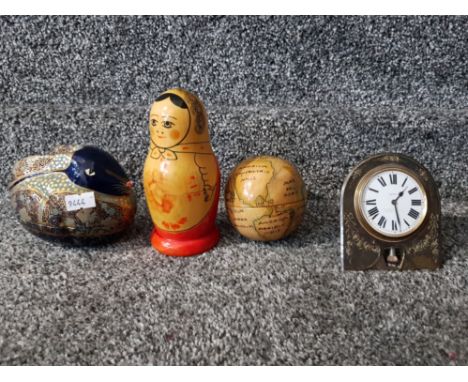 An early 20th century travelling clock in plated frame, a Russian doll and two other ornaments.