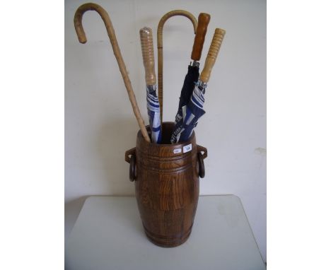 Oak barrel shaped stick stand with two ring handles and a selection of walking sticks and umbrellas 