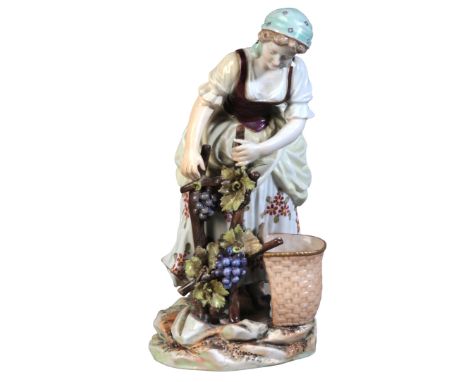 A CONTINENTAL PORCELAIN FIGURE OF A GRAPE HARVESTER19th century, bearing a Vienna style beehive mark, the lady wearing a gree