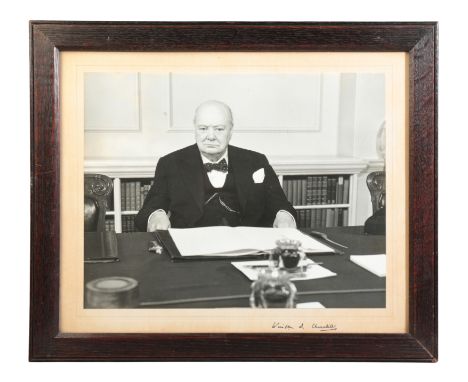 SIR WINSTON CHURCHILL INTEREST: A SIGNED PHOTOGRAPHIC PORTRAITdepicting the enigmatic statesman seated at his desk, signed in