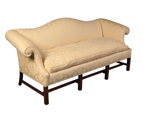 A GEORGE III STYLE MAHOGANY CAMEL BACK SOFA with golden damask covers, the scrolled arms over a square seat, on moulded block