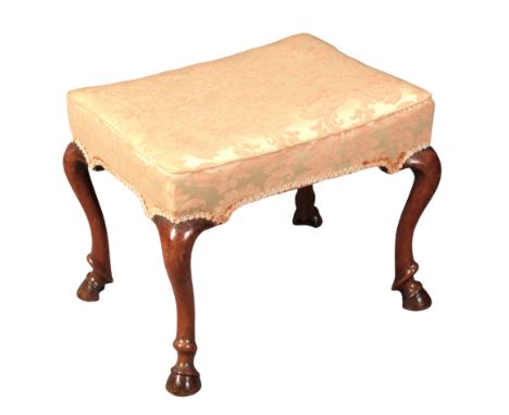 A QUEEN ANNE STYLE WALNUT STOOL the padded rectangular seat with damask covers on cabriole legs terminating in hoof feet, 42c