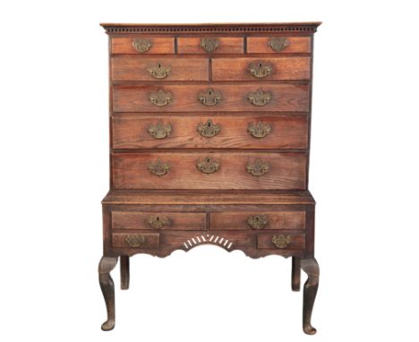 A GEORGE II OAK CHEST ON STAND mid 18th century, the upper section with a dentil moulded cornice over five short and three lo