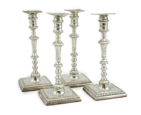 A matched set of four George III silver candlesticks, with knopped waisted stems, on square bases, two engraved with monogram