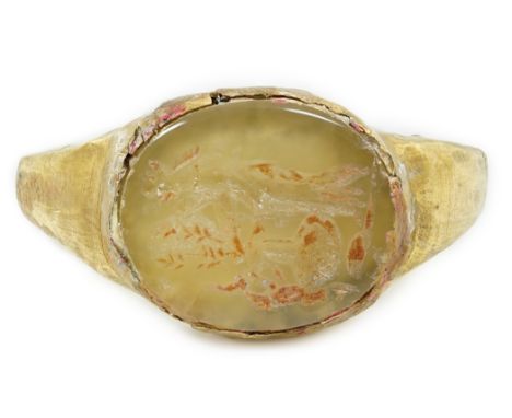 A Roman gold and hardstone intaglio military finger ring, carved with Saturn beside a pedestal, with angular shank, size Q/R,