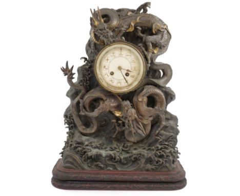 A Japanese parcel gilt bronze ‘dragon’ mantel clock, Meiji period, modelled with two dragons amongst waves, the ivory dial wi