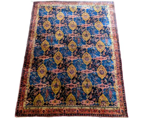 A Khorassan Mashhad red ground carpet, circa 1930’s, with field of stylised floral motif medallions, multi-bordered, 545 x 40