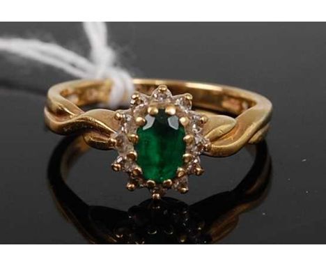 An 18ct gold, emerald and diamond cluster ring, the oval cut emerald in a surround of twelve diamond points, total diamond we