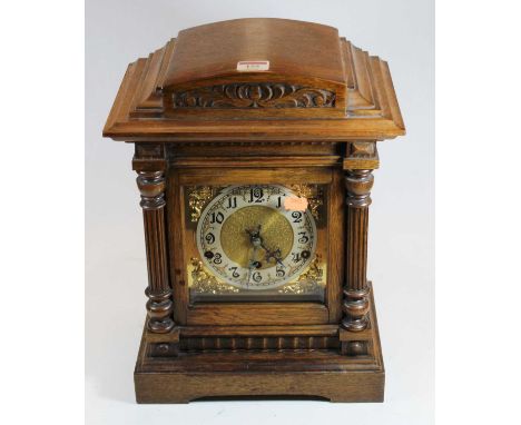 A circa 1900 Continental walnut cased mantel clock, having a silvered dial with Arabic numerals, within gilt brass spandrels,