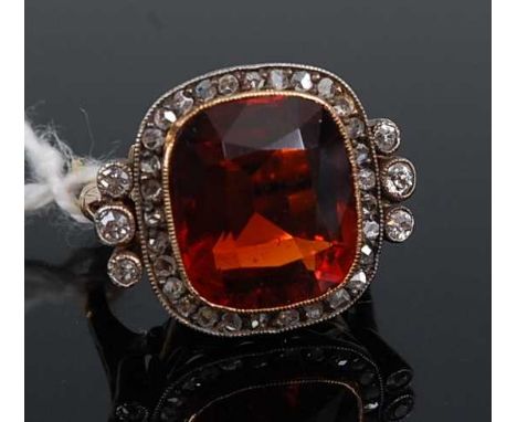 An 18ct gold orange quartz and diamond set dress ring, circa 1920s, the oval cut quartz measuring approx 13x11x7.5mm within a