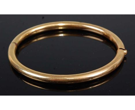 A plain yellow metal hinged bangle, 13.9g, unmarked but tests as approx  14ct, 7cm