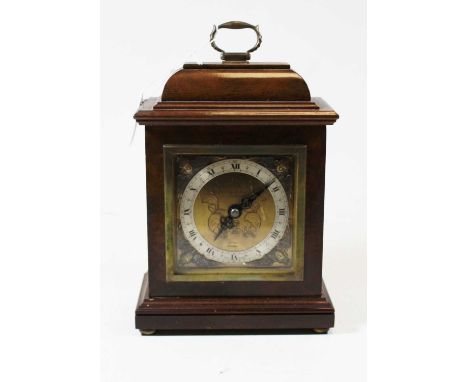 A walnut cased mantel clock, in the 18th century style, having a silvered dial with Roman numerals, within gilt cherub spandr