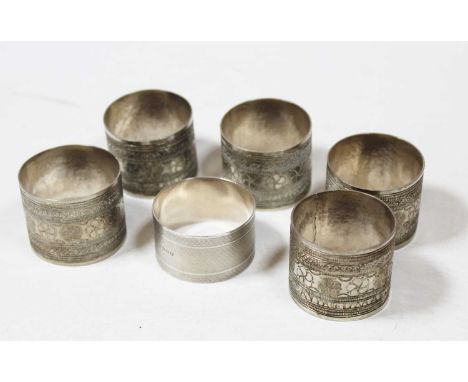 Five various Middle Eastern white metal napkin rings, each with engraved banded decoration, together with a George V engine t