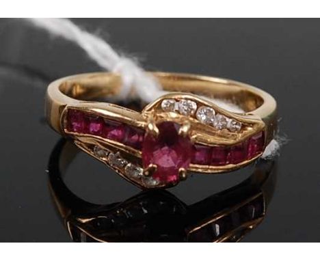 A contemporary 14ct gold, ruby and diamond set dress ring, arranged as a centre four-claw set oval ruby flanked to either sid