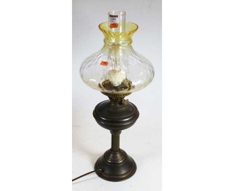 An early 20th century brass pedestal oil lamp, having yellow tinted glass shade, 56cm