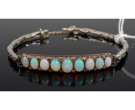 A white and yellow metal bracelet, set with nine graduated opal cabochons, each split with twin diamond highlights, all in no