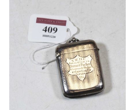 An Edwardian silver vesta of hinged rectangular form having engine turned decoration and shield shaped cartouche engraved "NW