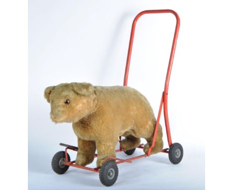 A vintage Pedigree made ride along / push along bear on a Lines Bro / Triang red metal stand with black rubber wheels. The be