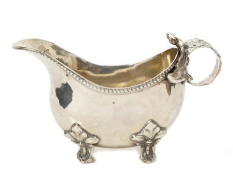 Late 19th century German silver sauce boat of inverted helmet form, with beaded border, heavy floral cast loop handle, on fou