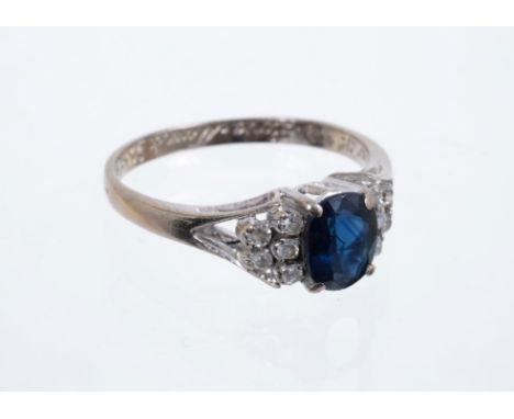 Sapphire and diamond ring with an oval mixed cut blue sapphire flanked by ten single cut diamonds in 18ct white gold setting,