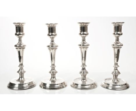 Set of four George V silver candlesticks of tapering form, with inverted bell-shaped stems and campana-style candle holders, 