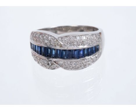 Sapphire and diamond ring with a band of calibre cut blue sapphires flanked by a crossover border of pavé set brilliant cut d
