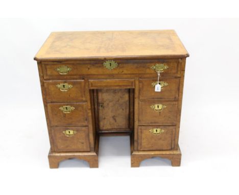 George II and later figured walnut featherbanded and crossbanded kneehole desk, the quarter-veneered top with re-entrant angl