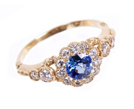 Sapphire and diamond flower cluster ring with a round mixed cut blue sapphire surrounded by a border of eleven brilliant cut 