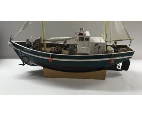 Another remote control boat, named "Bristol Bay" with a model fishing crew, some remote controls and R/C batteries.
