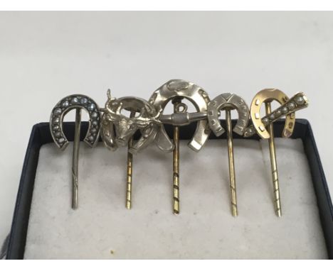 Five silver and gold horseshoe stick pins.