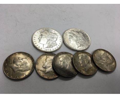Two 19th Century American Morgan Dollars and five 1964 half dollars.