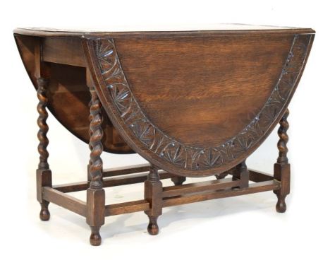 Oak two flap oval gate leg dining table having a carved edge and standing on barley twist supports united by stretchers   Con