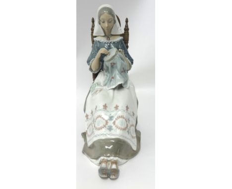 A Lladro figure modelled as a seated nun cross stitching, 27cm tall