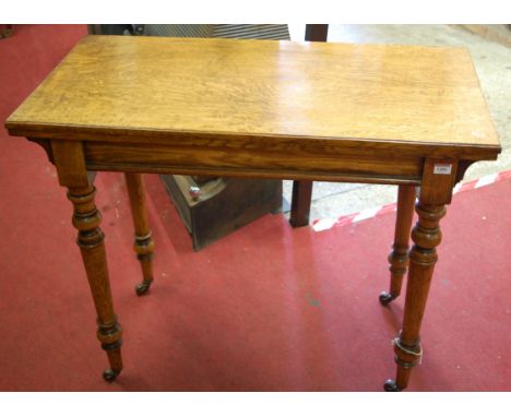 A late Victorian oak foldover card table, having revolving action and raised on turned and tapering supports 