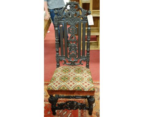 A Carolean style carved and ebonised oak single dining chair having bright coloured tapestry stuff over seat