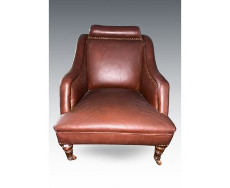 A Victorian brown rexine upholstered easy chair, bolster style headrest, sloped arms, on walnut legs, the front two of turned