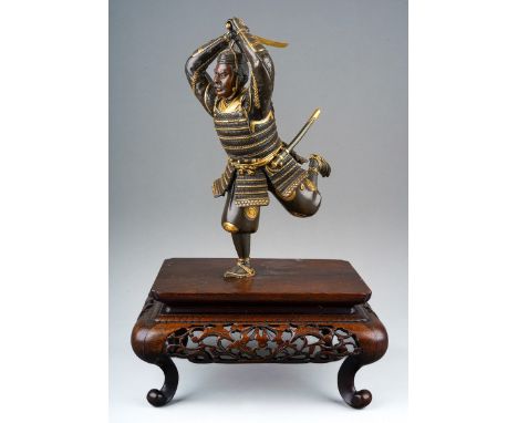 A Japanese Meiji period (1868-1912) parcel gilt bronze figure of a Samurai warrior with sword, finely cast details, both hand