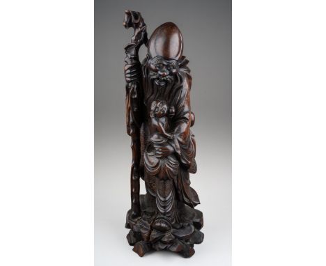 A Chinese carved hardwood figure of a elder with a staff and holding a child , silver wire inlay, carved as standing on a nat