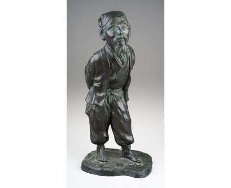 A 20th century Japanese cast bronze figure of a man holding his hands behind his back, standing on a naturalistic base, appea