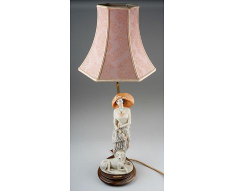 A Dear Studio figural table lamp, with painted resin elegant lady with a dog at her feet, on a circular wooden base, labels a