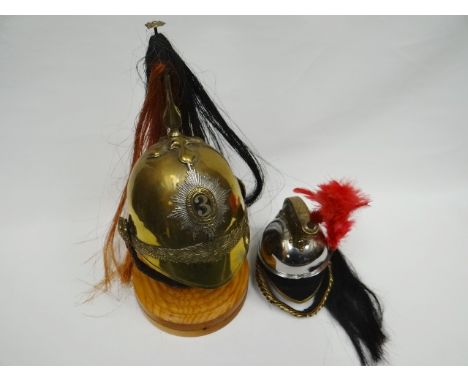 A half-size 3rd Dragoon Guards helmet with plumage and wooden stand together with French Cuirassier's miniature helmet 