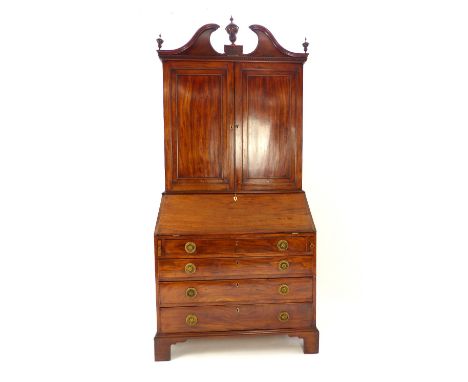 Georgian bureau bookcase, mahogany, swan neck pediment with urn finials, dentil band, twin doors concealing bookshelves, the 