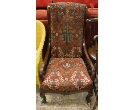 An early Victorian mahogany framed salon chair upholstered in red ground carpet raised on cabriole legs to white china castor