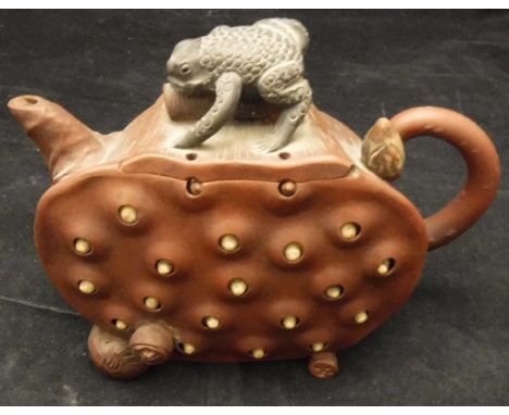 A 20th Century Yi Xing teapot as a cut lotus pod, the body with reticulated seeds, the lid decorated as a toad crawling upon 